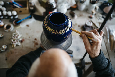 Senior man decorating ceramic vase in his spare time - JRFF000689