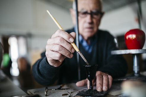 Senior man decorating ceramic in his spare time - JRFF000692