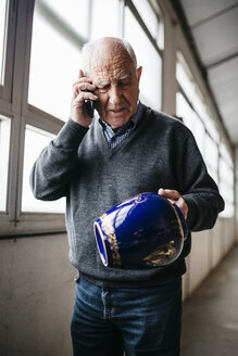 Elderly man reviewing the ceramic vase, talking on the phone - JRFF000694