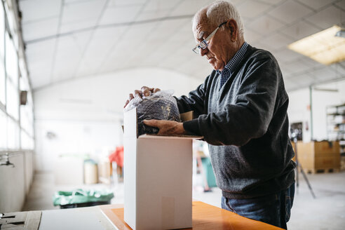 Senior man wrapping the finished ceramic piece - JRFF000697