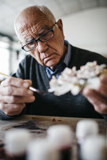 Senior man decorating ceramic in his spare time - JRFF000699