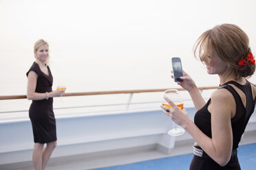 Laughing woman taking a picture of her friend on deck of a cruise liner - ONBF000029