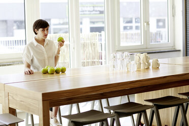 Portrait of woman in a modern canteen eating an apple - TSFF000021