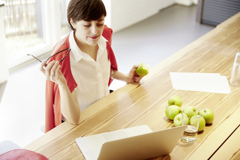 Frau in einer modernen Kantine isst einen Apfel, lizenzfreies Stockfoto