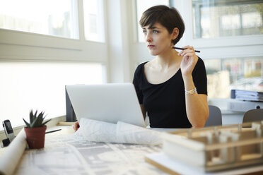 Architect sitting at desk looking through window - TSFF000036