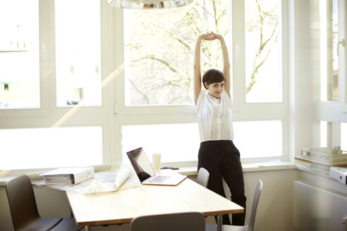 Woman doing stretching exercise in her office - TSFF000048