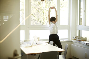 Woman doing stretching exercise in her office - TSFF000050