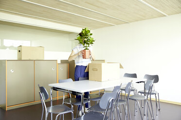 Frau versteckt sich hinter Topfpflanze in neuem Büro - TSFF000079