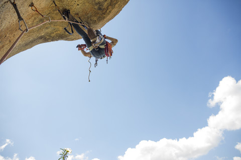 Kletterer, der einen Felsen mit Hilfe von Klettertechniken erklimmt, lizenzfreies Stockfoto