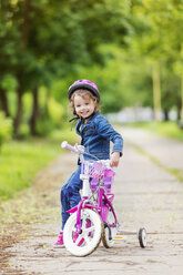 Lächelndes Mädchen auf Fahrrad mit Stützrädern - HAPF000488