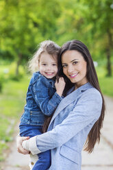 Portrait of mother holding daughter in park - HAPF000498