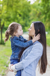 Mother holding daughter in park - HAPF000499