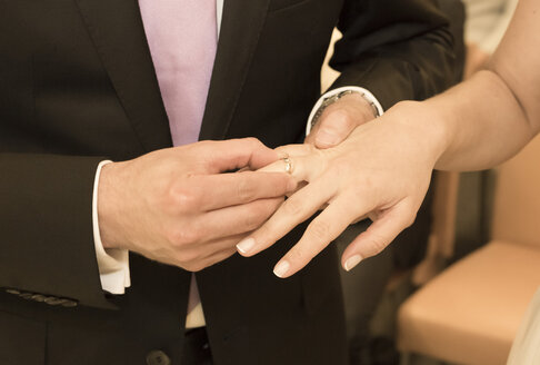 Bräutigam steckt der Braut den Ehering an die Hand - FCF000969