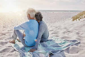 Rückenansicht eines Paares, das am Strand sitzt und auf das Meer blickt - RORF000199