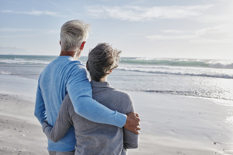 Rückenansicht eines Paares am Strand mit Blick aufs Meer, lizenzfreies Stockfoto