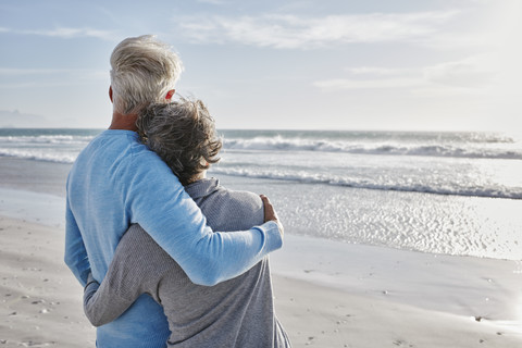 Back view of couple on the beach looking to the sea stock photo