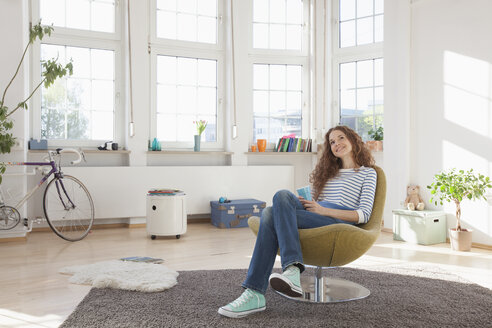 Entspannte Frau zu Hause auf einem Stuhl sitzend - RBF004551