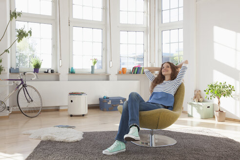 Entspannte Frau zu Hause auf einem Stuhl sitzend - RBF004552