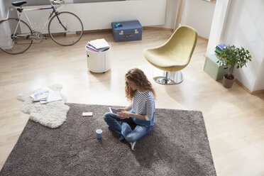 Frau zu Hause auf dem Boden sitzend mit digitalem Tablet - RBF004574