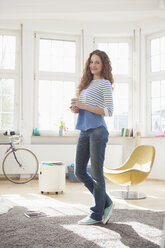 Smiling woman at home holding cup of coffee - RBF004575