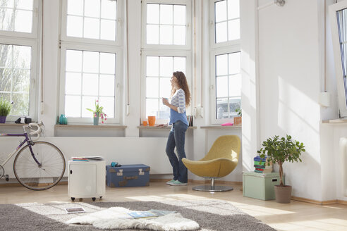 Frau zu Hause schaut aus dem Fenster - RBF004576