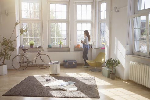 Frau zu Hause schaut aus dem Fenster - RBF004583