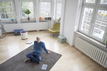 Entspannter reifer Mann zu Hause auf dem Boden sitzend - RBF004589