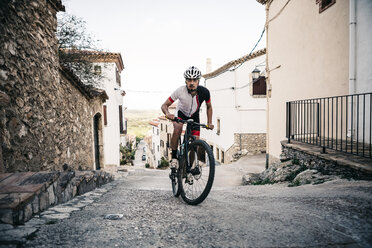 Mountainbiker beim Bergauffahren in einem Bergdorf - JRFF000726