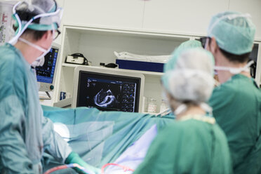 Heart surgeons and operating room nurse looking at monitor - MWEF000067