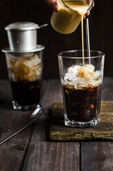 Pouring sweetened condensed milk over vietnamese iced coffee - SBDF002902