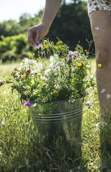 Frauenhand berührt Blüte von Wildblumen in einem Eimer - DEGF000816