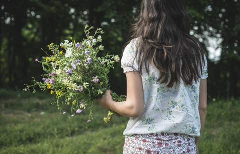 Rückenansicht einer Frau, die einen Strauß Wildblumen hält, lizenzfreies Stockfoto