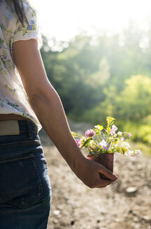 Frau hält kleinen Eimer mit Wildblumen in der Hand - DEGF000819