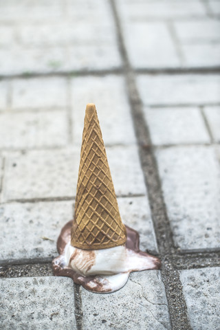 Eistüte mit schmelzender Schaufel, die kopfüber auf dem Boden liegt, lizenzfreies Stockfoto