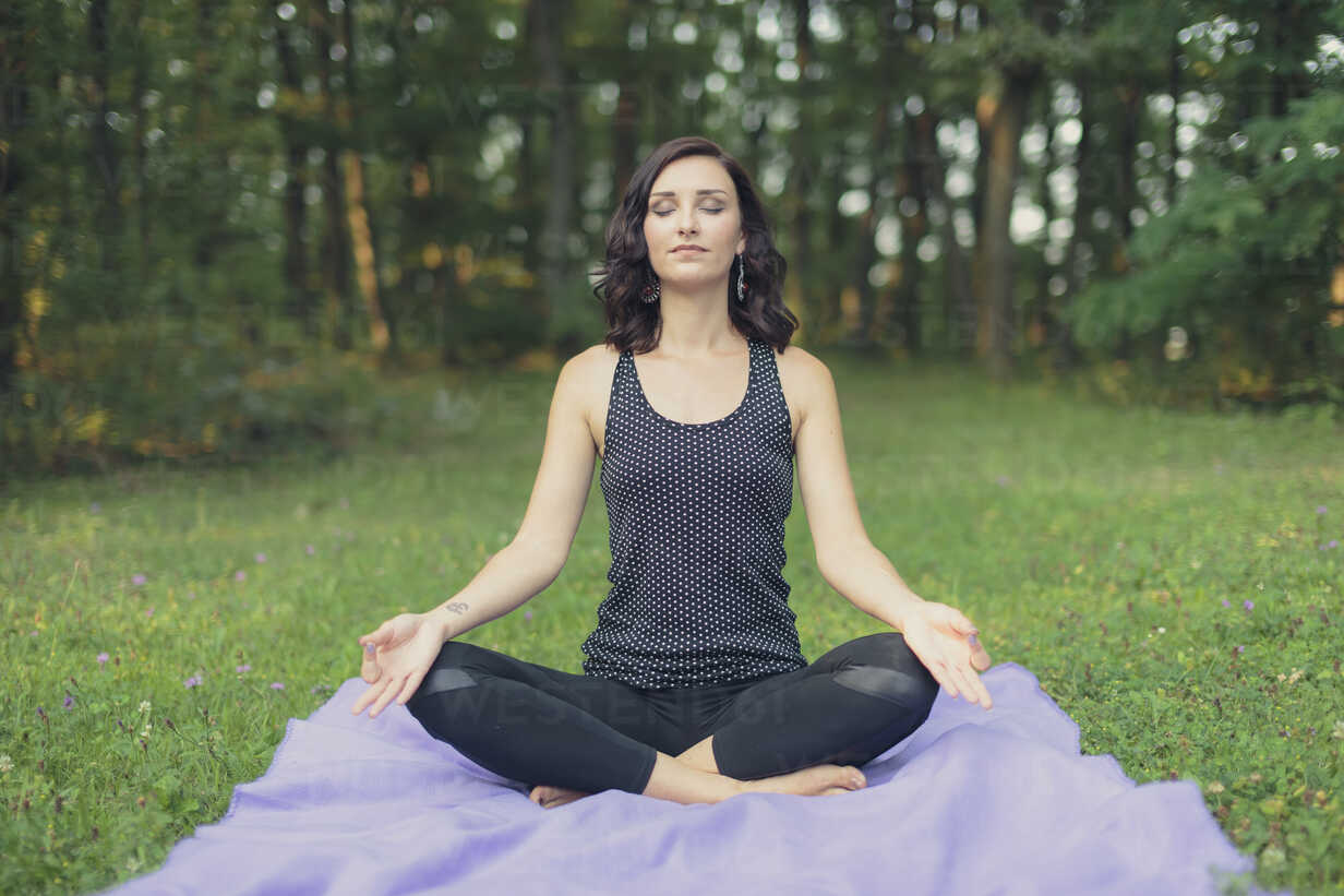 Croatia, Woman meditating in lotus position, yoga in nature stock photo