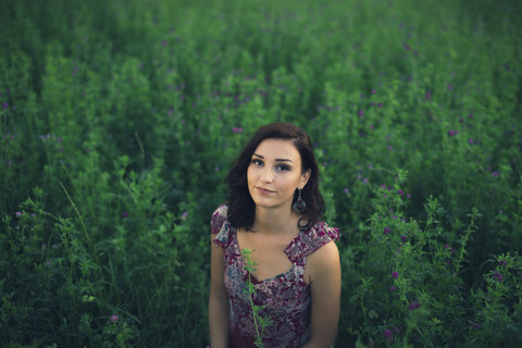 Porträt einer im hohen Gras sitzenden Frau, lizenzfreies Stockfoto