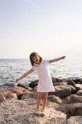 Italien, Brenzone, kleines Mädchen mit ausgestreckten Armen am Seeufer stehend - LVF004918