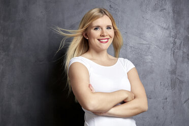 Portrait of smiling blond woman in with crossed arms - FMKF002701