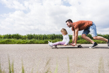 Vater schiebt Tochter auf Skateboard - UUF007399