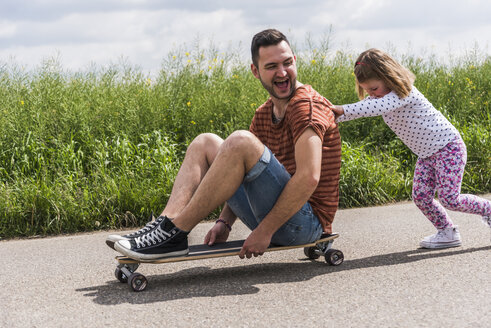 Tochter schiebt Vater auf Skateboard - UUF007402