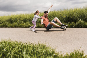 Tochter schiebt Vater auf Skateboard - UUF007403