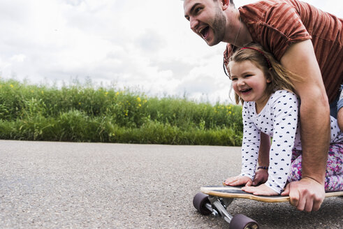 Daughter with father on skateboard - UUF007404