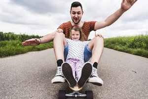 Tochter und Vater sitzen auf einem Skateboard - UUF007408