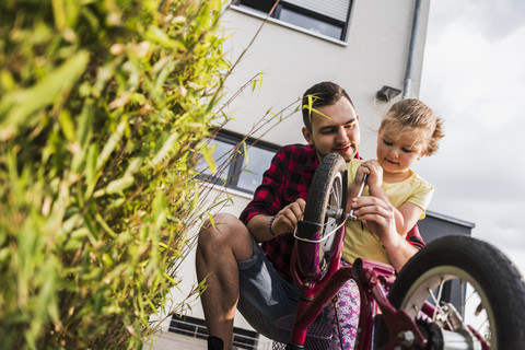 Vater und Tochter reparieren gemeinsam ein Fahrrad, lizenzfreies Stockfoto