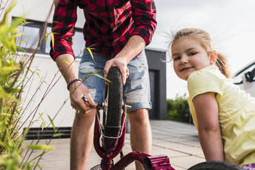 Vater und Tochter reparieren gemeinsam ein Fahrrad - UUF007418