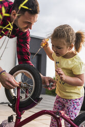 Vater und Tochter reparieren gemeinsam ein Fahrrad - UUF007419