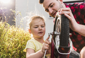 Father and daughter repairing bicycle together - UUF007422