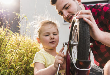 Vater und Tochter reparieren gemeinsam ein Fahrrad - UUF007422