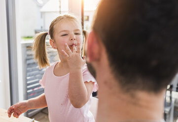 Girl with finger in mouth looking at father - UUF007429