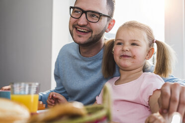 Happy father and daughter having breakfast together - UUF007436